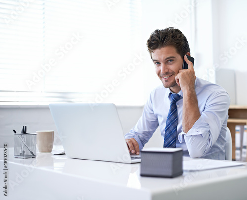 Sure, we can do that for you. A young businessman talking on the phone while seated at his desk.