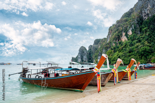 Wooden long tail boat anchored on the beach in Phi Phi island and limestone mountain at Krabi