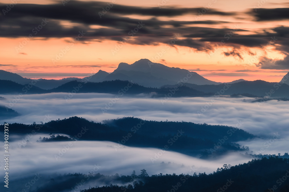 Sunrise over mountain range and sea of fog flowing on hill in national park