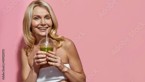 Canvas Print Pleased mature woman drinking cocktail or juice