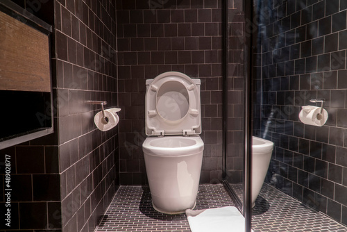 Black bathroom have white toilet and white towel