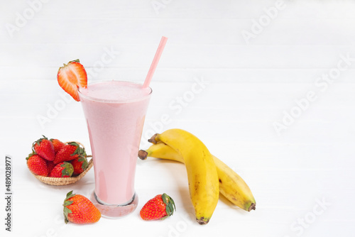 Strawberry and banana smoothie colorful fruit juice milkshake blend beverage healthy high protein the taste yummy In glass drink episode morning on a white wooden background.