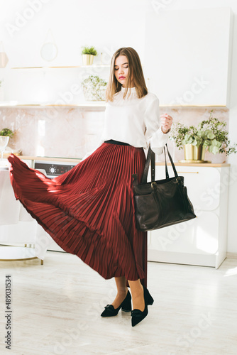 Portrait of fashionable women in a red skirt, white blouse and stylish suedeshoes with a buckle posing on the kitchen photo