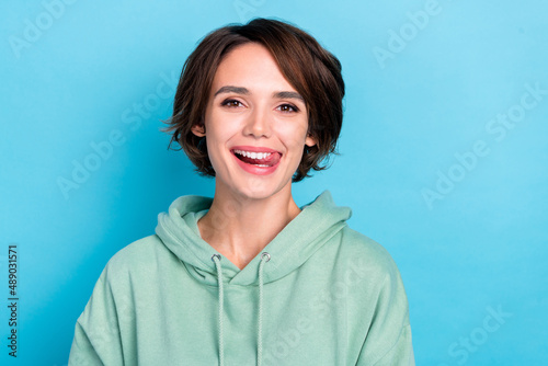 Photo of pretty shiny woman wear green sweatshirt showing tongue smiling isolated blue color background