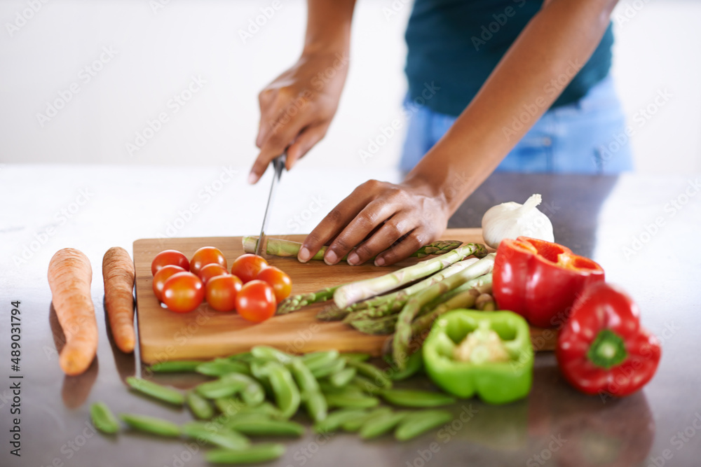 Preparing a healthy and wholesome meal. Cropped closeup shot of a woman cutting up vegetables on a cutting board. Preparing a healthy and wholesome meal. Cropped closeup shot of a woman cutting up vegetables on a cutting board.