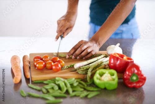 Preparing a healthy and wholesome meal. Cropped closeup shot of a woman cutting up vegetables on a cutting board.