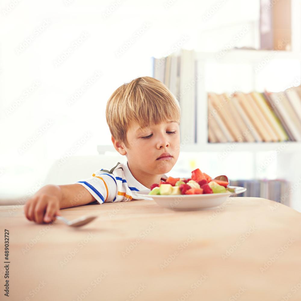 Unenthusiastic about fruit. A young boy looking at a bowl of fruit unenthusiastically. Unenthusiastic about fruit. A young boy looking at a bowl of fruit unenthusiastically.