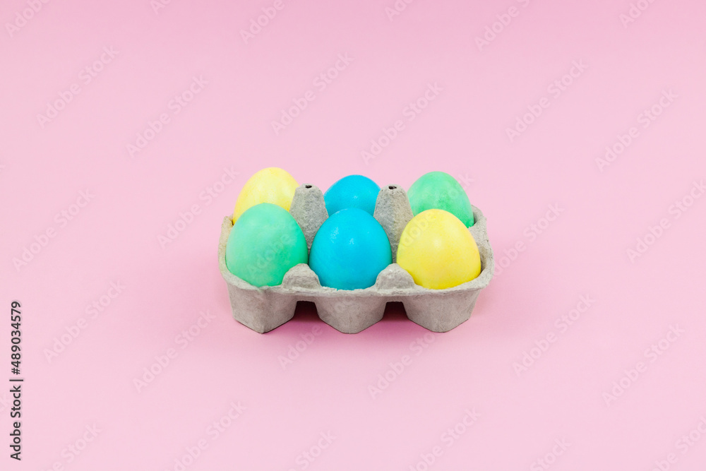 Box with colorful Easter eggs on a pink background