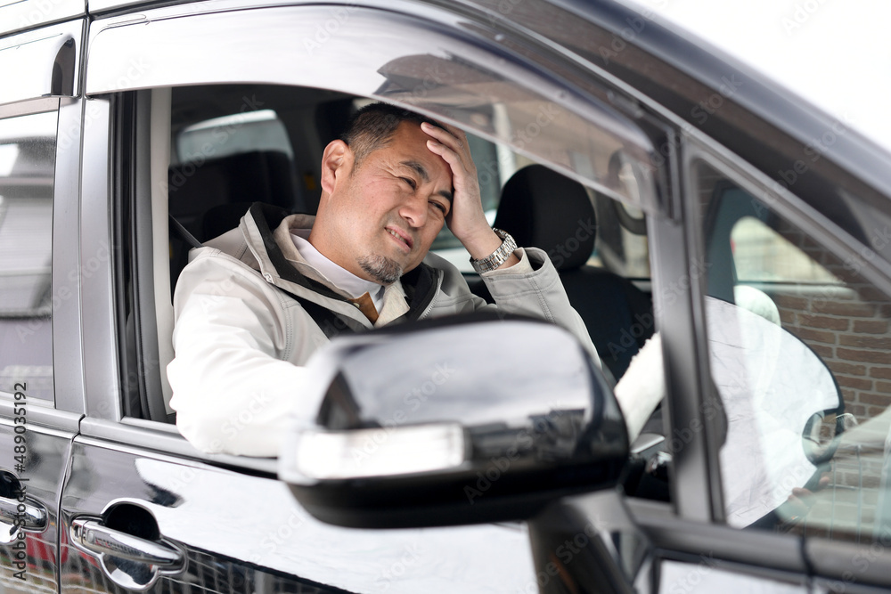 不安な表情をする車を運転中のミドル男性 不安な表情をする車を運転中のミドル男性