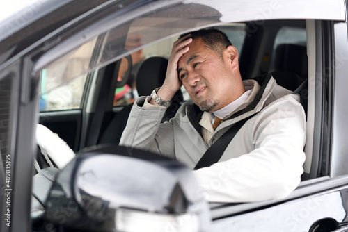 不安な表情をする車を運転中のミドル男性 © koumaru