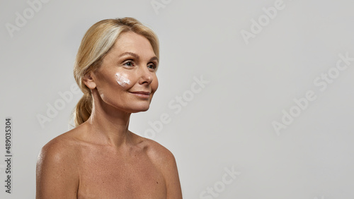 Woman with cosmetic cream on her face looking away