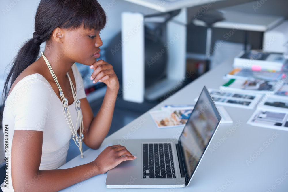 Working hard on her designs. Shot of the inner workings of a creative and modern office. Working hard on her designs. Shot of the inner workings of a creative and modern office.