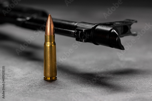 One bullet against Kalashnikov assault rifle. Cartridge 7.62 caliber for ak 47 closeup. Selective focus photo