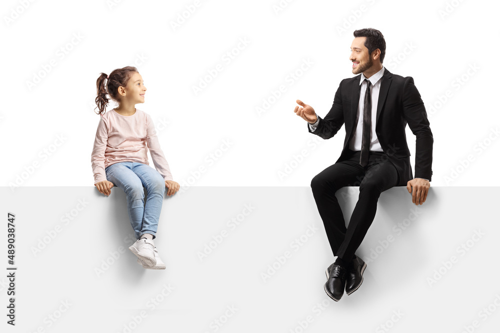 Businessman sitting on a blank panel and talking to a little girl Businessman sitting on a blank panel and talking to a little girl