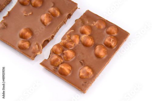 Macro photo of Chocolate bar. Broken pieces over white background. Pieces of milk chocolate with nuts isolated on white background