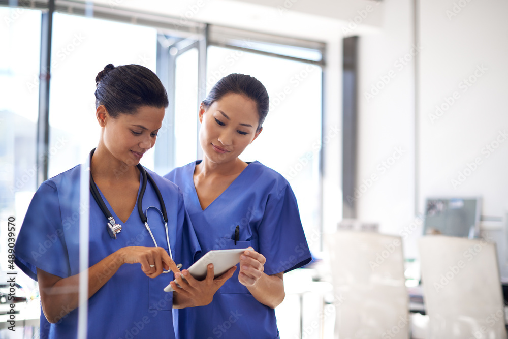 © Daniel Laflor/peopleimages.com - Reviewing patient data. Shot of two female nurses using a tablet to review medical records.