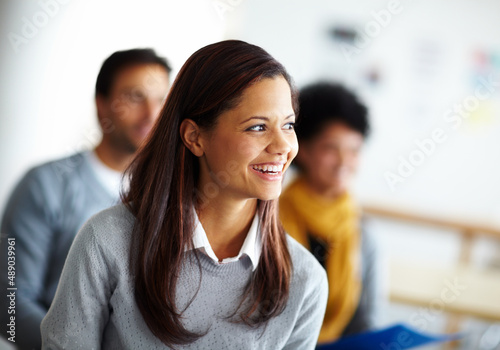 Shes sharp and smart. A beautiful young woman sitting and listening to a presentation at work.