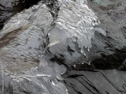 Close-up view of grey rock covered with ice. Extremal winter weather 