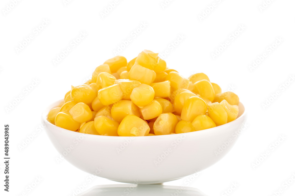 Bright yellow canned corn kernels in white ceramic saucer, macro, isolated on white background. Bright yellow canned corn kernels in white ceramic saucer, macro, isolated on white background.