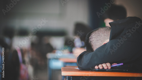 Fotografia Tired uniform students sleeping in a exam test in classroom with stress