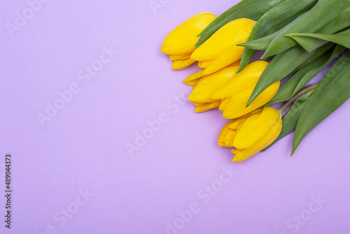 The spring composition is a bouquet of yellow tulips on a lilac background.