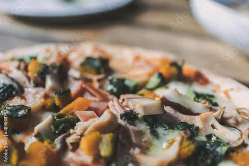Homemade Veggie pizza with mushroom and pumpkins served on rounded wooden plate.