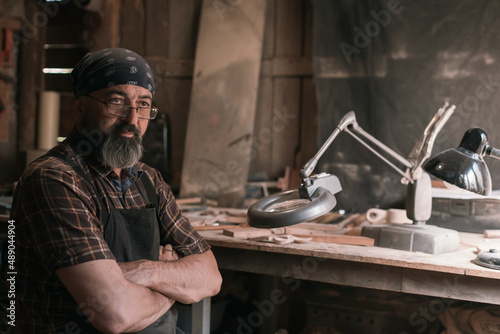 Spoon master in his workshop with wooden products and tools