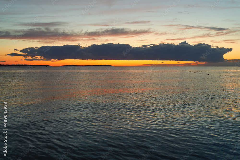 Long big dark cloud over the sea at sunset