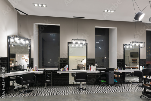 Interior of the barbershop with mirrors, chairs and other equipment near windows