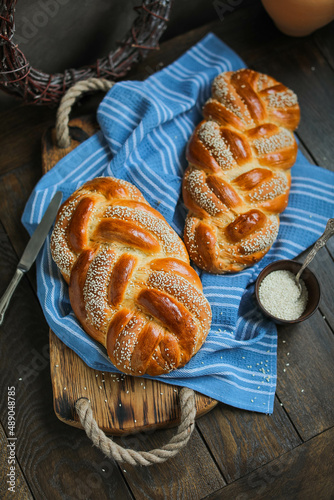 Sweet braided buns with sesame seeds on a blue kitchen towel. Sweet yeast pastry photo