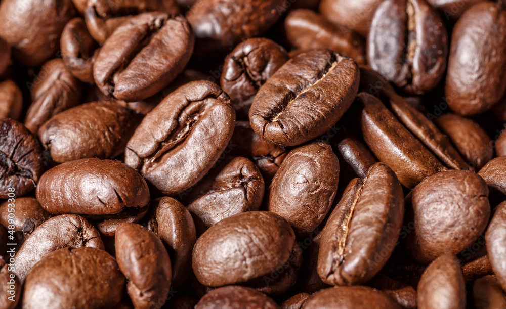 Fototapeta premium Freshly roasted coffee beans background.Dark roasted coffee beans with scoop on wooden background.