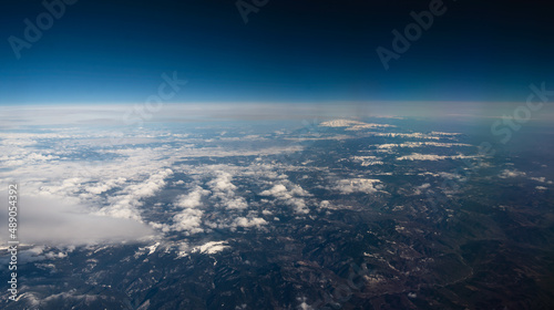Photography view from the airplane window to mountains clouds and blue sky