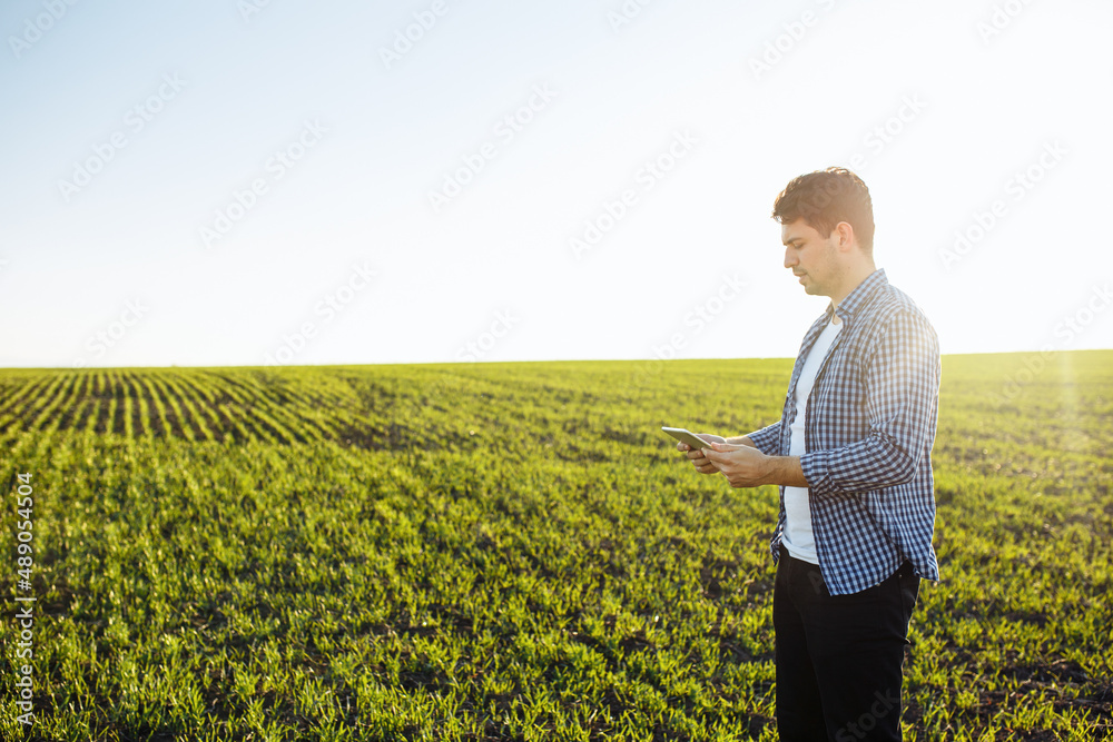 Young agronomist check the data from the tablet and compares the new wheat seeding progress with expectations. Technologies and farming concept. Young agronomist check the data from the tablet and compares the new wheat seeding progress with expectations. Technologies and farming concept.
