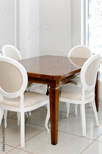 Wooden polished table and chairs in the kitchen in a classic style. Vertical photo. © natavilman