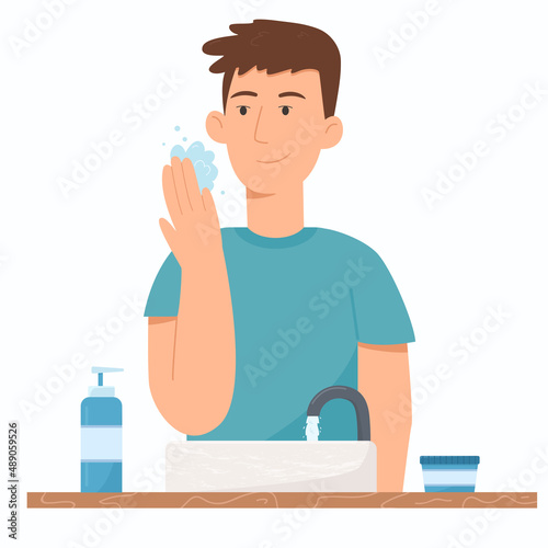 Man using gel foam for washing face in bathroom near sink. Cosmetic for men.