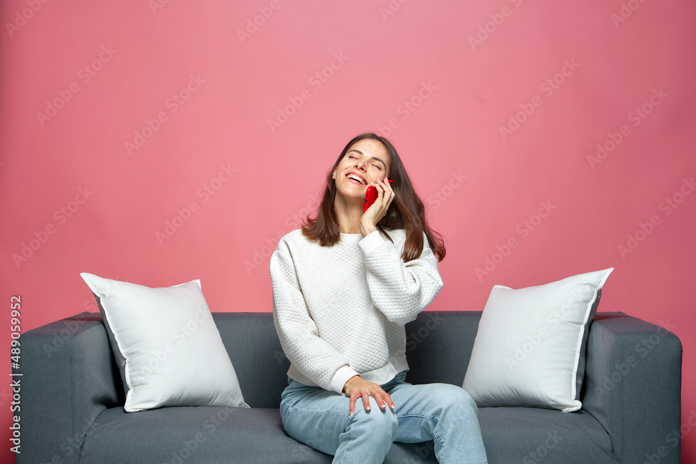 Smartphone call. Friendly laughing young woman chatting with friend on phone, sharing good news, sitting on sofa Smartphone call. Friendly laughing young woman chatting with friend on phone, sharing good news, sitting on sofa