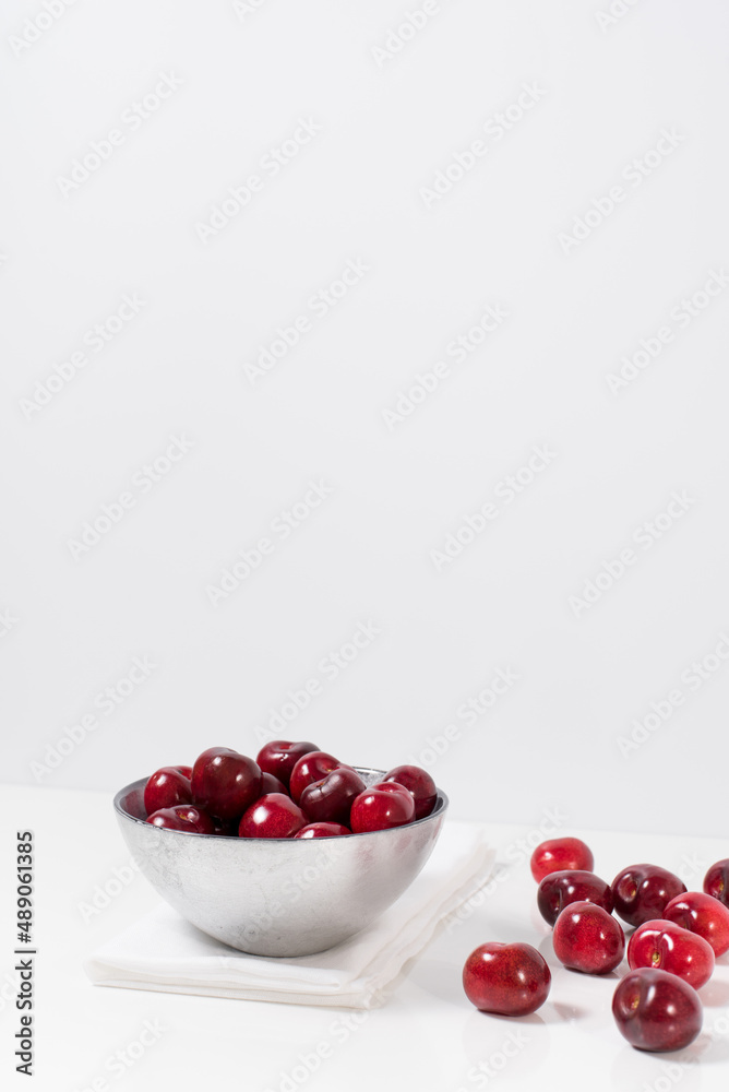 Cerezas dulces rojas en un recipiente de plata y fondo blanco Cerezas dulces rojas en un recipiente de plata y fondo blanco