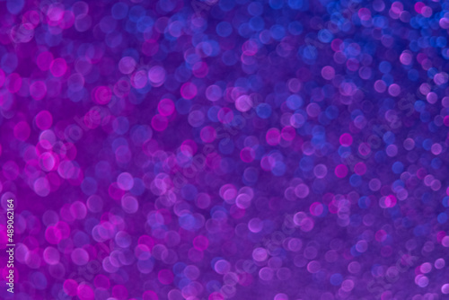 Neon bokeh light. Glitter overlay. Blur festive glitz sparkles. Defocused fluorescent purple blue pink color glow shimmering circles pattern abstract background.