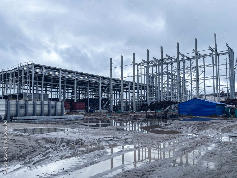 metal warehouse for storage of building materials. a large warehouse with barrels. warehouse construction, bare raw structure, metal frame metal warehouse for storage of building materials. a large warehouse with barrels. warehouse construction, bare raw structure, metal frame
