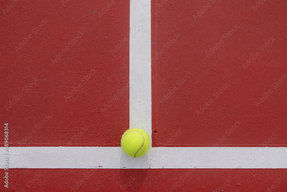 Tennis ball on the serving line of a red tennis court