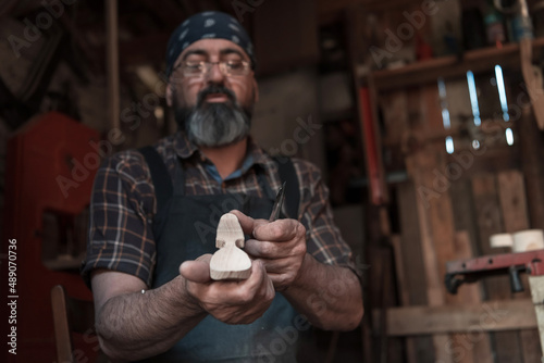 Spoon craft master in his workshop with handmade wooden products and tools working 