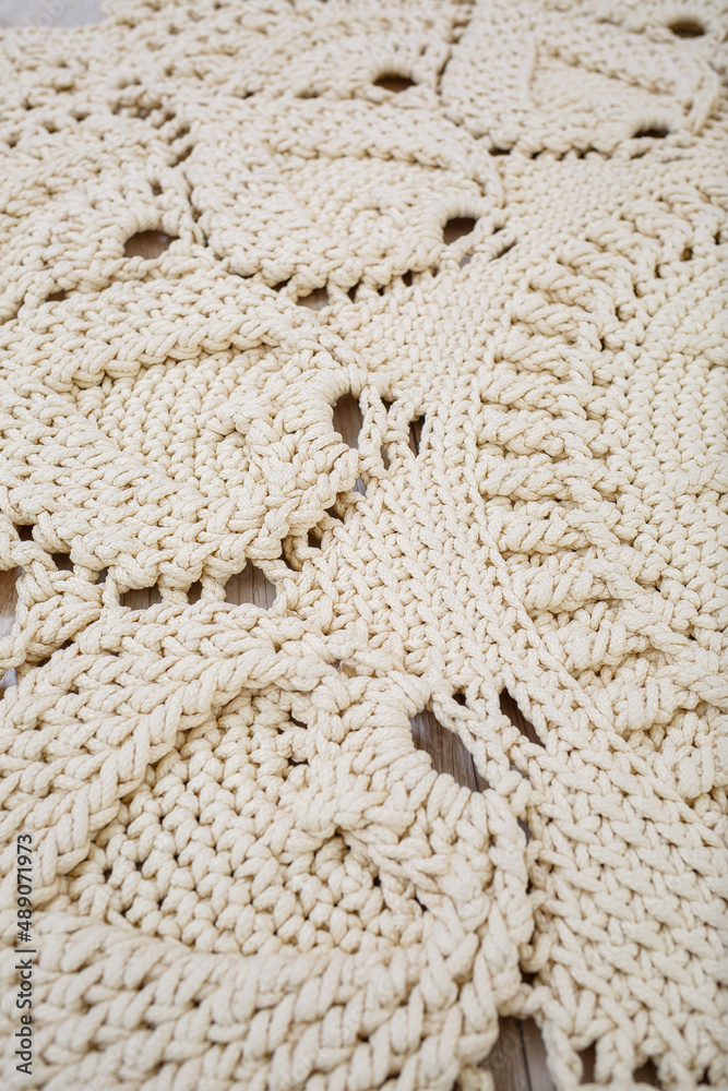 Handmade carpet knitted from natural threads, flooring, natural cotton. Beige handmade carpet. Knitted decorative item