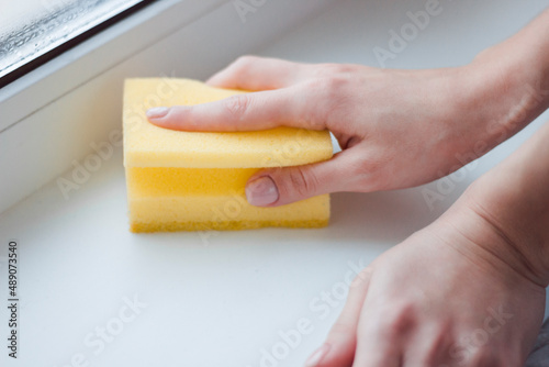 The girl washes the window with a sponge. Home routine. Cleaning  photo