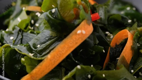 Eating Wakame Seaweed salad with carrots, sesame seeds and sauce