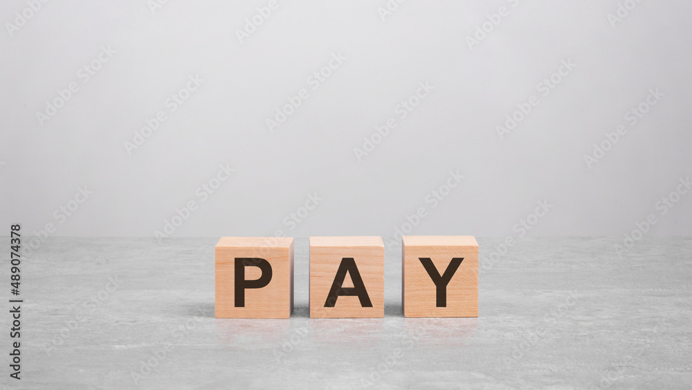 three wooden blocks with the letters PAY on the gray table. business concept three wooden blocks with the letters PAY on the gray table. business concept