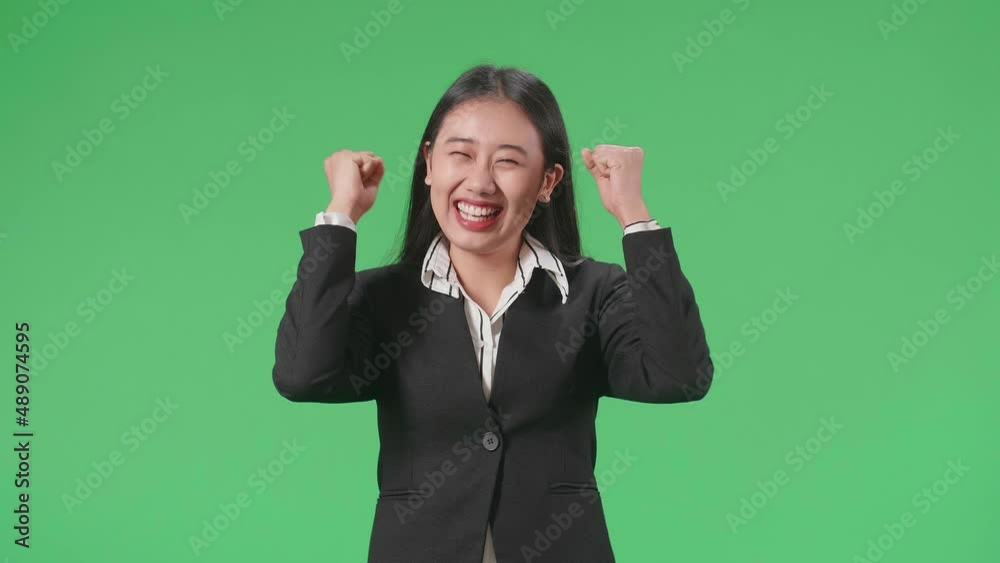 Happy Asian Business Woman Celebrating While Standing On Green Screen In The Studio
