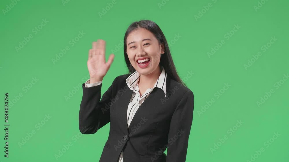 A Smiling Asian Business Woman Waving Hand Saying Good Bye While Walking Through Green Screen In The Studio
A Smiling Asian Business Woman Waving Hand Saying Good Bye While Walking Through Green Screen In The Studio