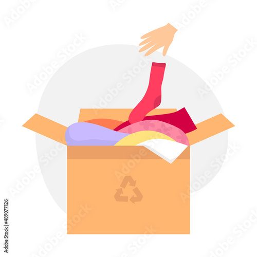 Cardboard box with old clothes for clothing recycling. The hand throws the sock into the box