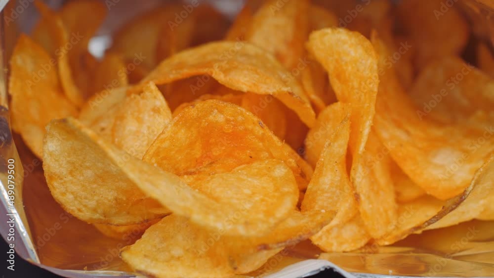 Crispy fried potato chips on a black background. A detailed snapshot of lying potato chips.
