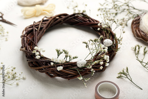 Easter wreath with eggs and gypsophila flowers on light background